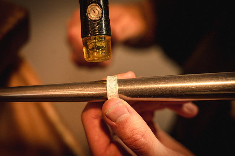 Arbeitesszene eines Goldschmiedes, die das hämmern eines Ringes zeigt. 